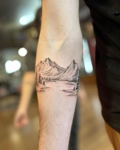 a person with a tattoo on their arm and the image of mountains is shown in black ink