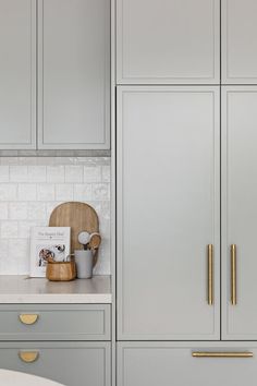 a kitchen with gray cabinets and gold handles on the doors, along with a white counter top