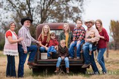 a family poses in the back of an old pickup truck for their photo session with one child and two adults