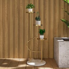 three potted plants sitting on top of a metal stand next to a wooden wall