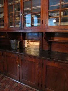 an old wooden china cabinet with glass doors and cupboards on the top, in a kitchen