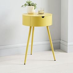 a yellow table with a potted plant on it and a glass cup sitting on top