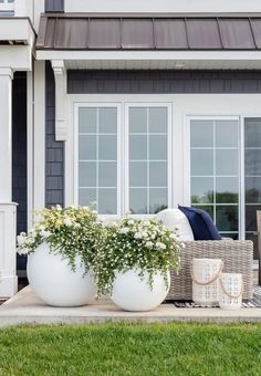 two large white vases sitting on top of a wooden deck next to a house