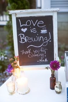 a chalkboard sign that says love is brewing and two vases filled with flowers