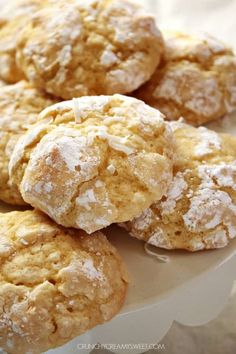 several powdered sugar cookies are on a white platter and ready to be eaten