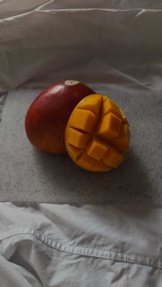 two pieces of fruit sitting on top of a white bed sheet next to each other