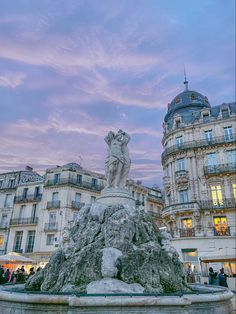 a statue in front of some buildings at dusk