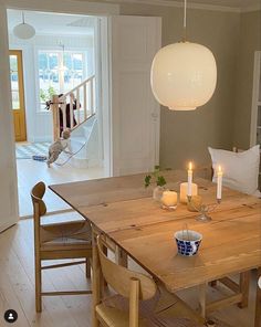 a dining room table and chairs with candles on it in front of a doorway that leads to another room