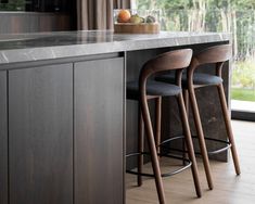 two bar stools sit at the end of a counter in front of an open window