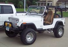 a white jeep parked next to a white truck