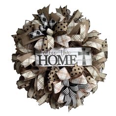 a wreath with the words home on it and bows hanging from it's side