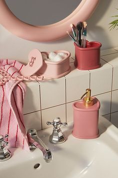 a bathroom sink with pink towels and toothbrushes