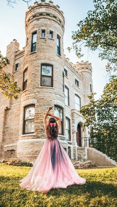 a woman standing in front of a castle like building with pink and blue tulle skirt