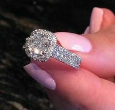 a woman's hand holding an engagement ring with two diamonds on the top and bottom