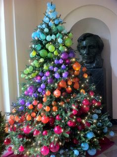 a brightly colored christmas tree in the middle of a room with a busturine behind it