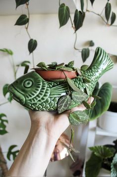 a hand holding a planter with a fish design on it