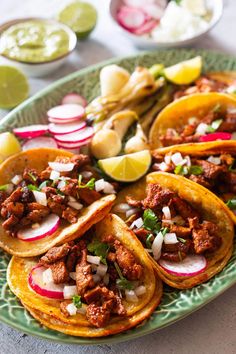 tacos with meat, onions and radishes are served on a green plate