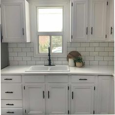 a kitchen with white cabinets and a window above the sink is shown in this image