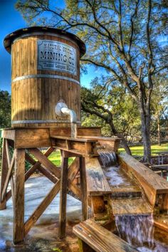 a wooden water tower sitting in the middle of a park next to benches and trees