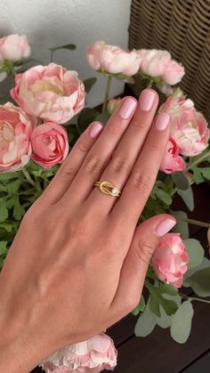 a woman's hand with pink manicured nails and a gold ring