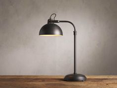 an industrial style desk lamp on top of a wooden table