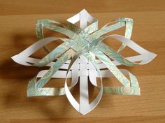 an ornament made out of white paper on a wooden table with scissors in it