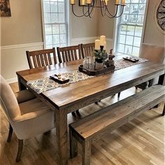 a dining room table with two benches in front of it and a chandelier hanging from the ceiling