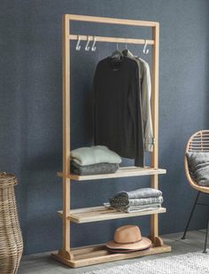 a clothes rack and chair in a room with blue walls, rugs and wicker furniture