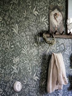 a bathroom with wallpaper, mirror and towel rack