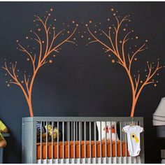 a baby's room with a crib and trees painted on the wall