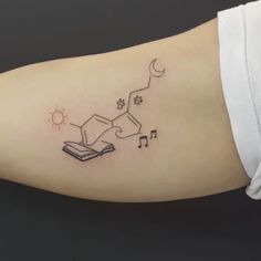 a person with a book and music notes tattoo on their arm