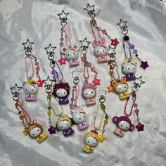 hello kitty keychains are lined up on a white sheet with stars and bows