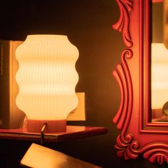 a lamp sitting on top of a wooden table next to a mirror and a book