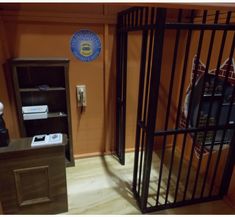 a jail cell with the door open and a sign on the wall in the background