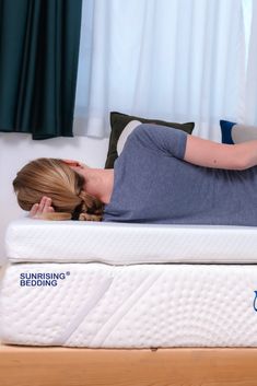 a woman laying on top of a white mattress