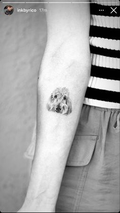 a small dog tattoo on the left forearm and right arm, it is black and white