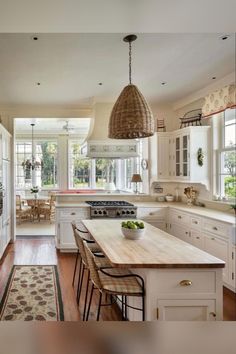 a large kitchen with white cabinets and wooden flooring, along with an island in the middle