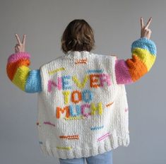 a woman wearing a colorful knitted jacket with the words love you much written on it