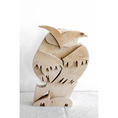 a wooden sculpture of an owl sitting on top of a white tablecloth covered floor