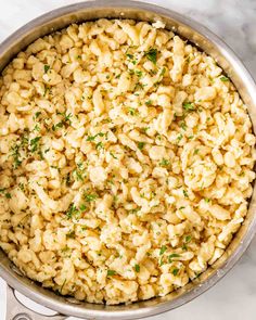 macaroni and cheese with parsley in a silver pot on a marble surface