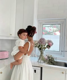 a woman in a white dress holding a child