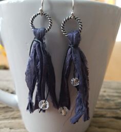 a pair of earrings with beads and tassels hanging from them on a cup