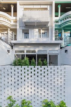 an apartment building with balconies and plants growing on the outside wall, in front of a white picket fence