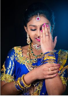 a woman in a blue sari holding her hands to her face