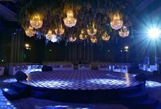 an empty dance floor with chandeliers hanging from the ceiling and lights shining down on it