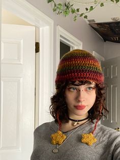 a woman wearing a multicolored knitted hat with yellow stars on her ear