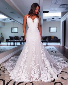 a woman in a white wedding dress standing on a carpeted floor looking back at the camera