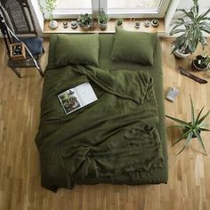 an overhead view of a bed with green sheets and pillows on the floor next to a window