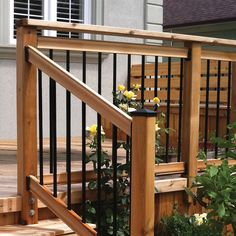 a wooden deck with black iron railing and flowers