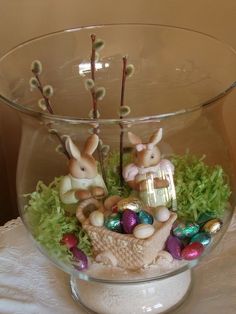 a glass bowl filled with easter decorations on top of a table